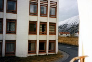 View from a window towards a building and a snow-covered mountainside