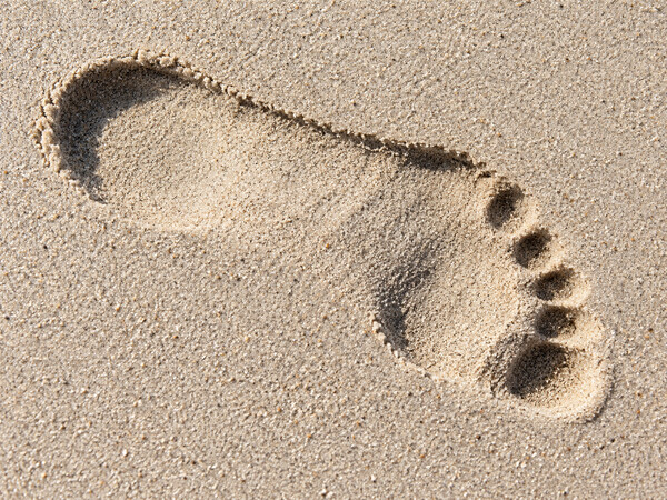 Einzelner Fußabdruck diagonal in hellem Sand.
